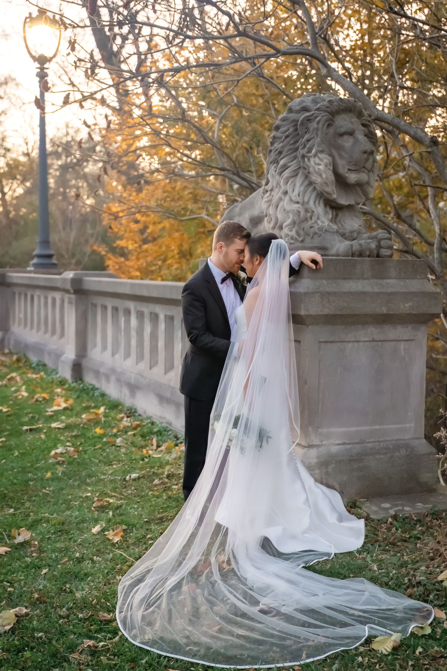 A couple in wedding attire playfully poses in a series of shots with the bride's flowing veil in an autumn outdoor setting.