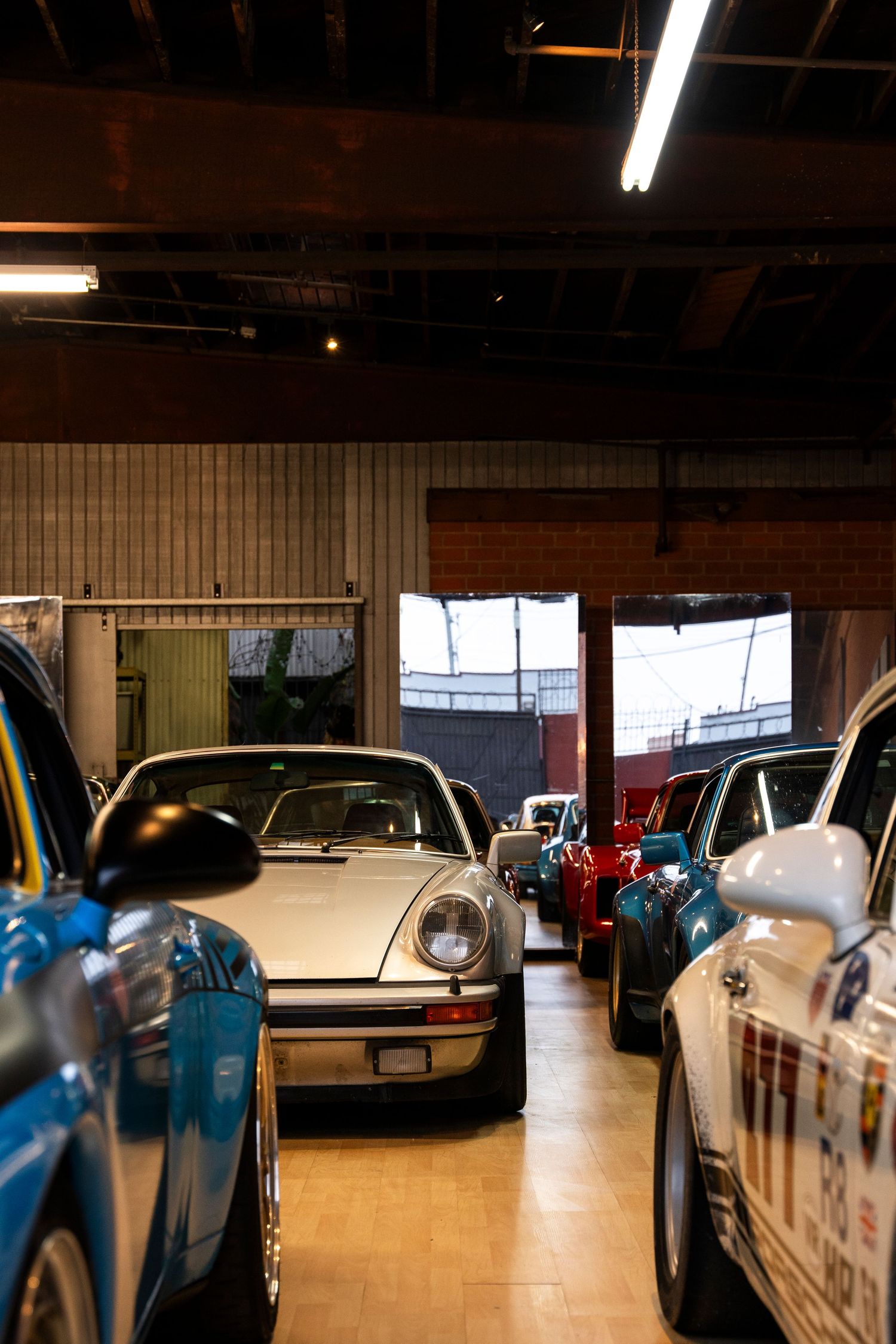 Sleek sports cars lined up in an indoor parking garage with fluorescent lighting overhead.