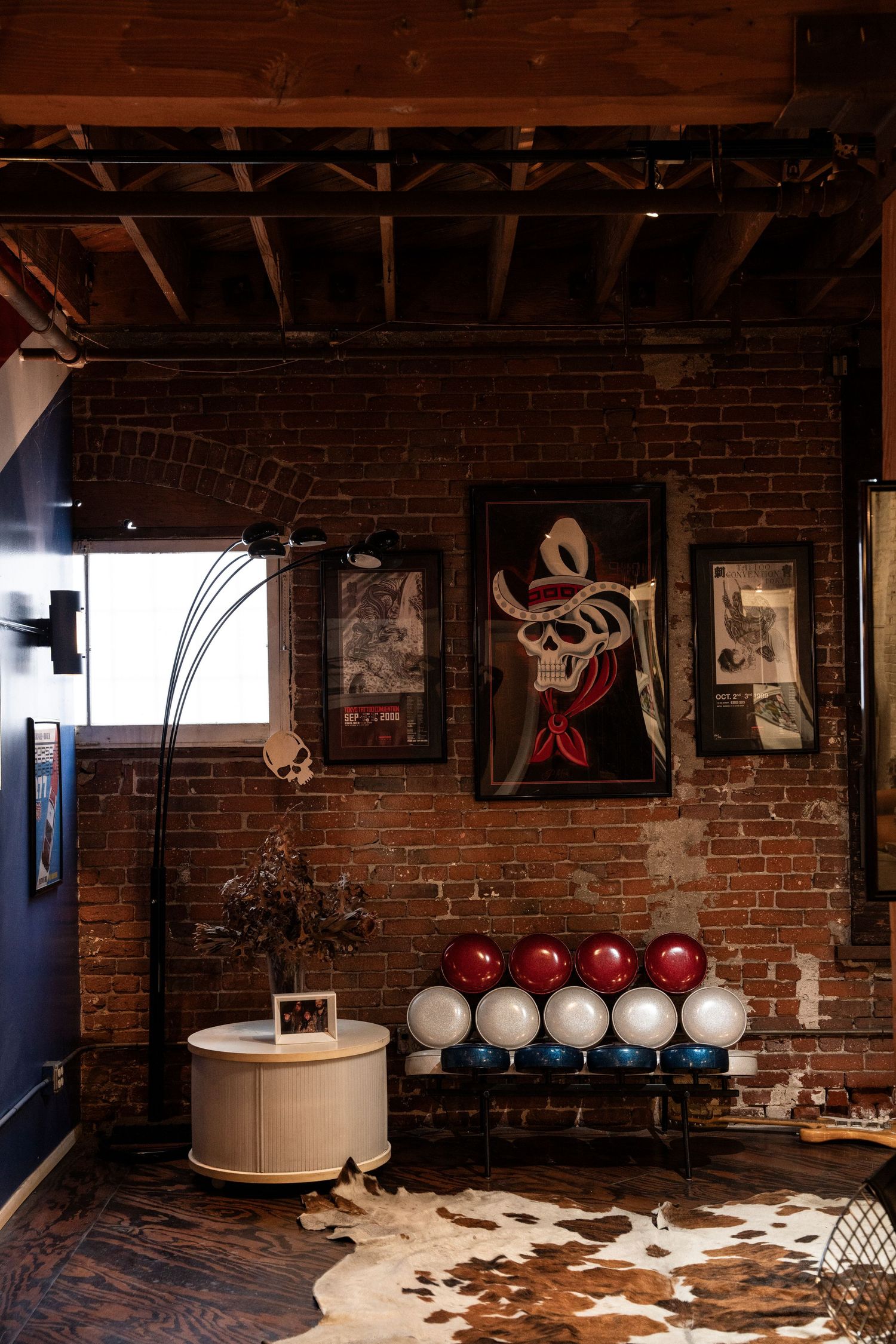 Rustic studio space with exposed brick walls, cowhide rugs, and pendant lighting creates an industrial chic atmosphere.
