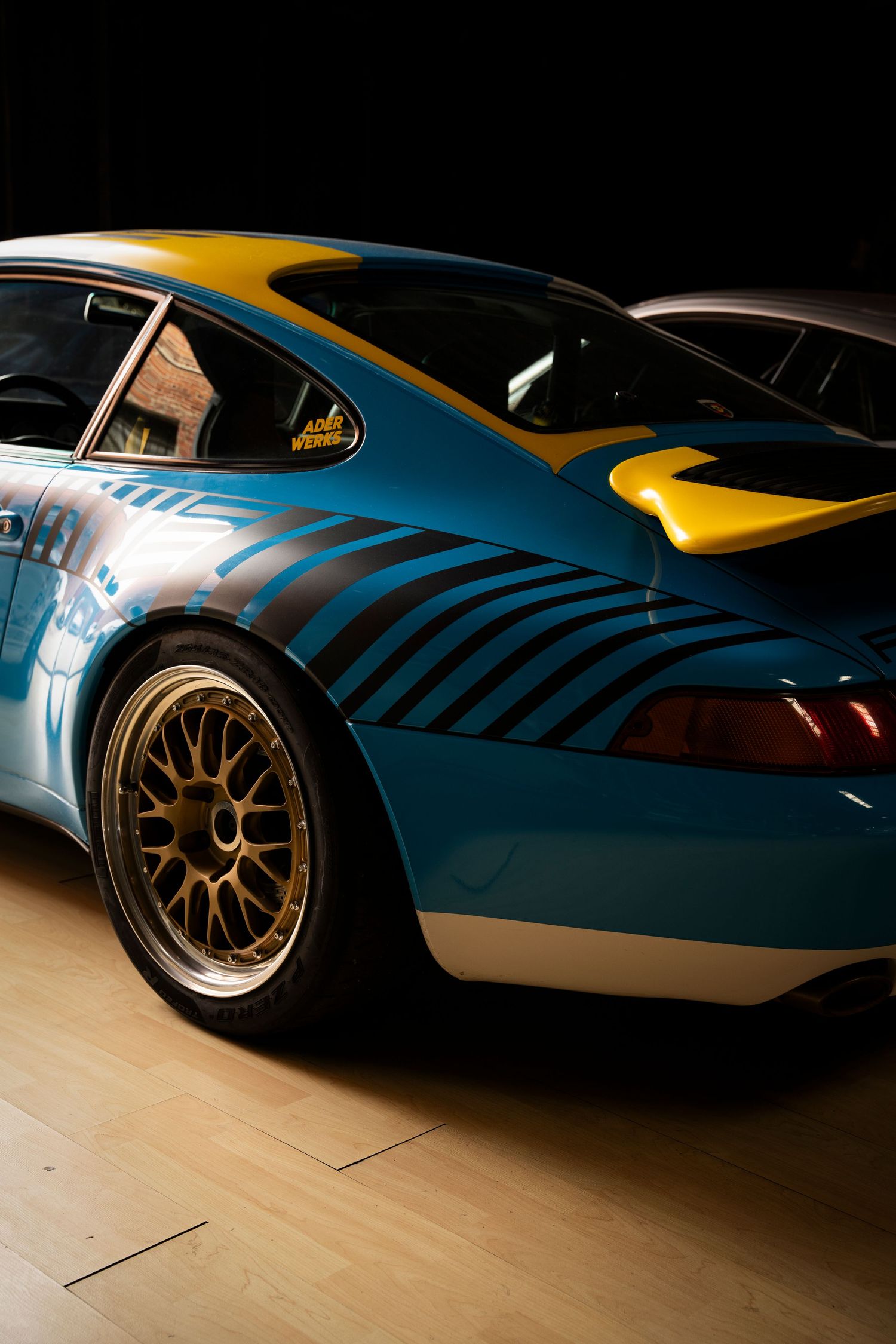 Close-up shots of a blue and yellow custom sports car showing sleek body panels and gold wheels in dramatic lighting.