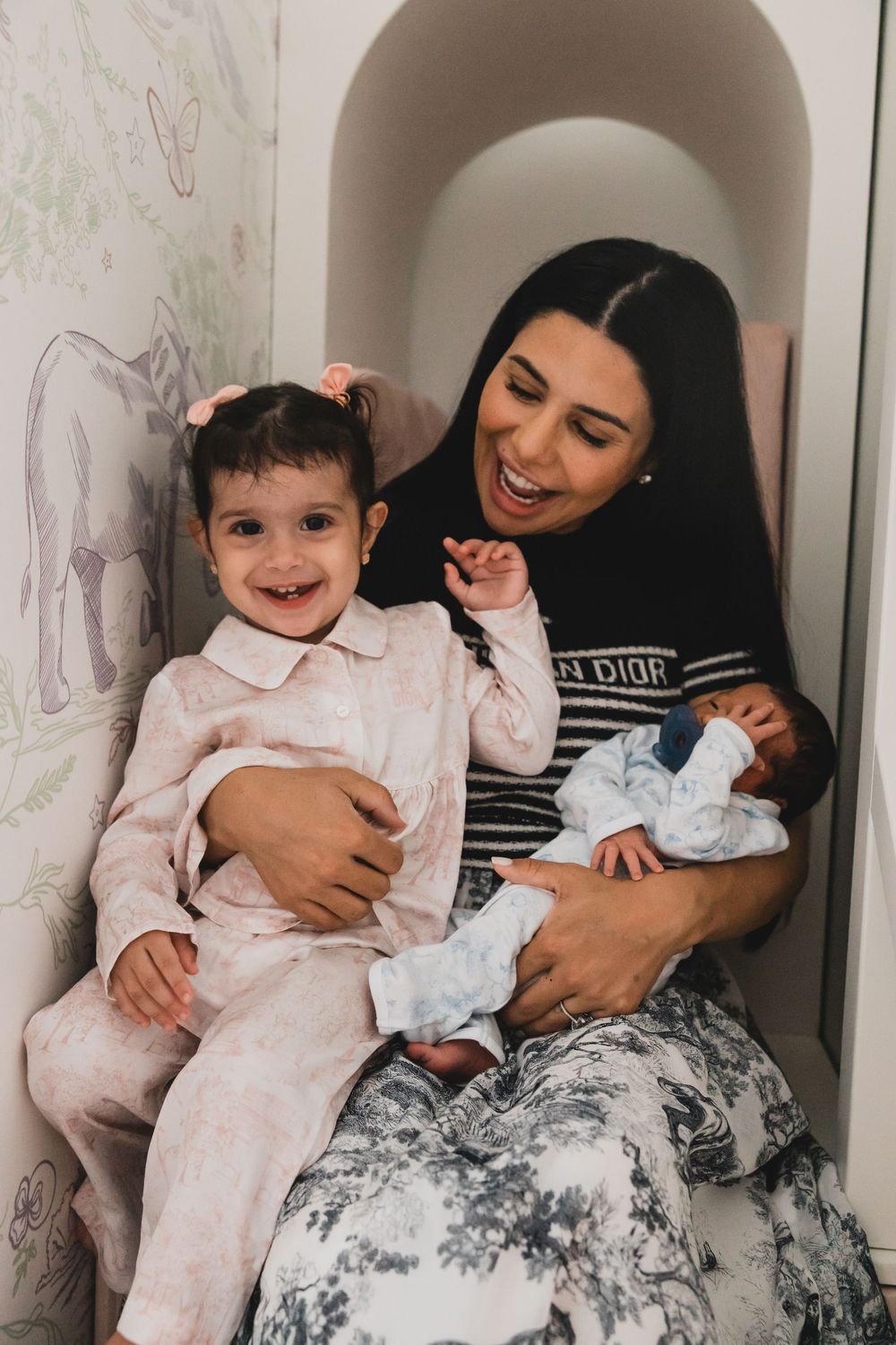 A parent and child share tender moments while sitting together in a tiled alcove with floral wallpaper.