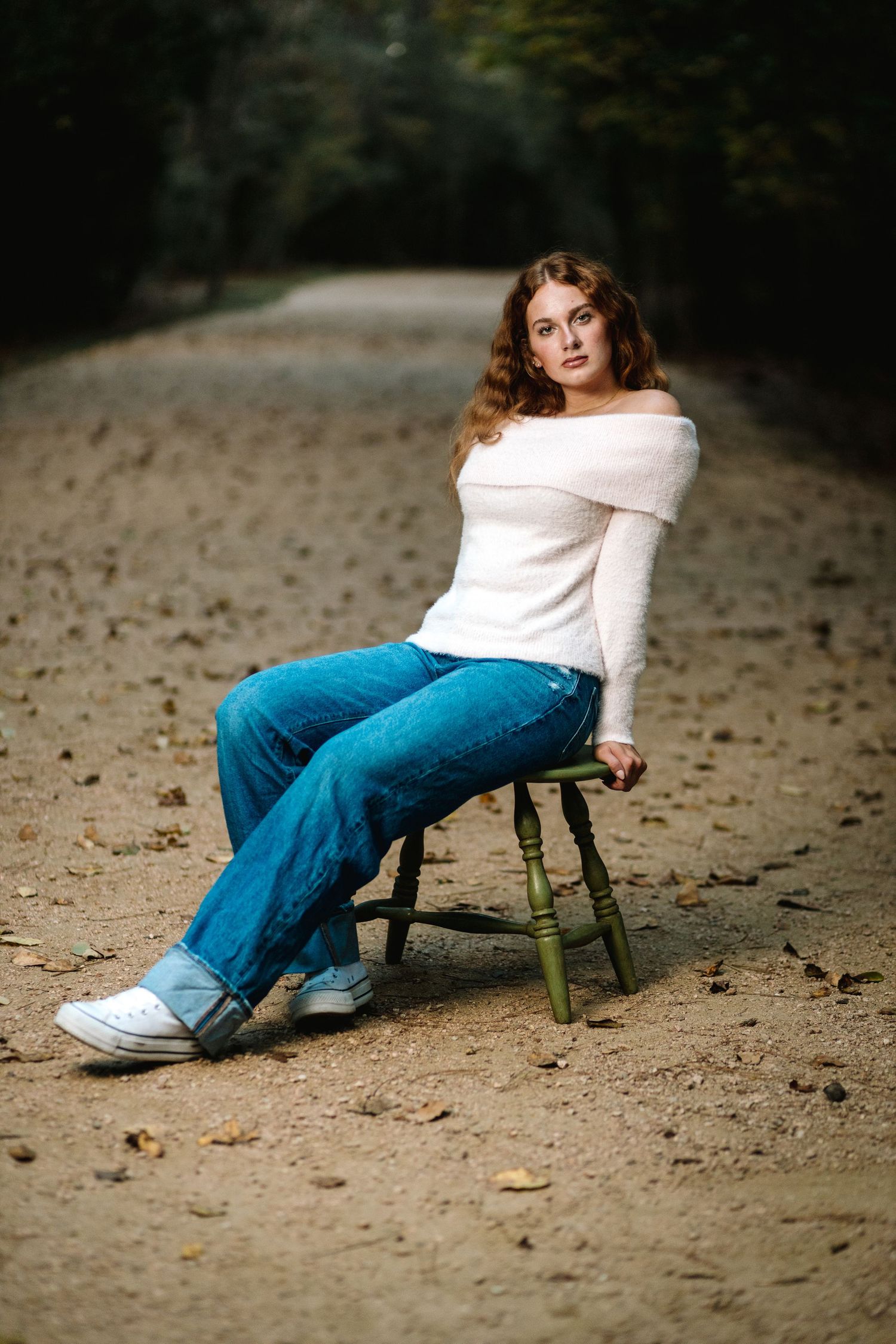 A series of artistic photos showing someone in blue jeans and white top posing on a green wooden chair outdoors.