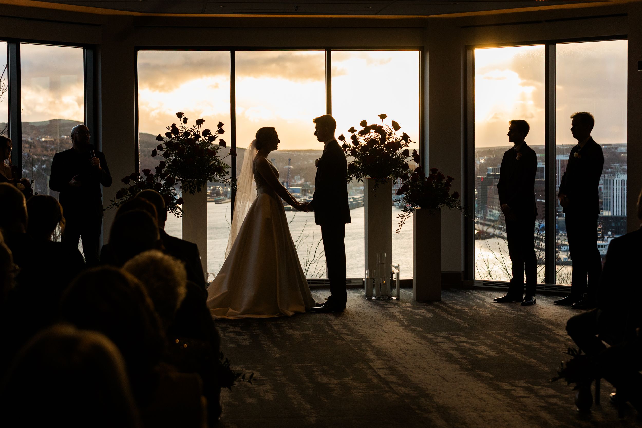 Silhouettes of people standing against large windows at sunset creating dramatic shadows and light.