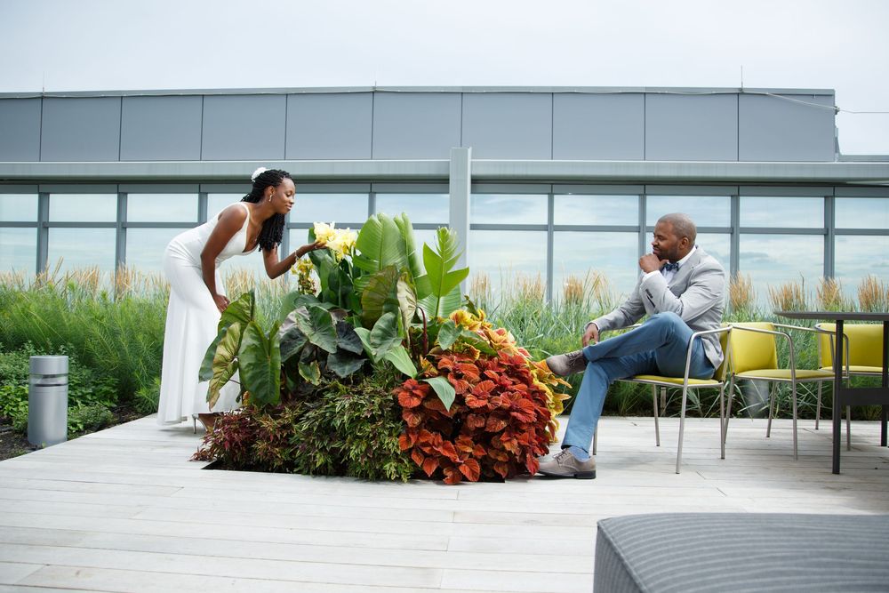 Modern rooftop terrace with grey outdoor furniture and planters against urban backdrop.