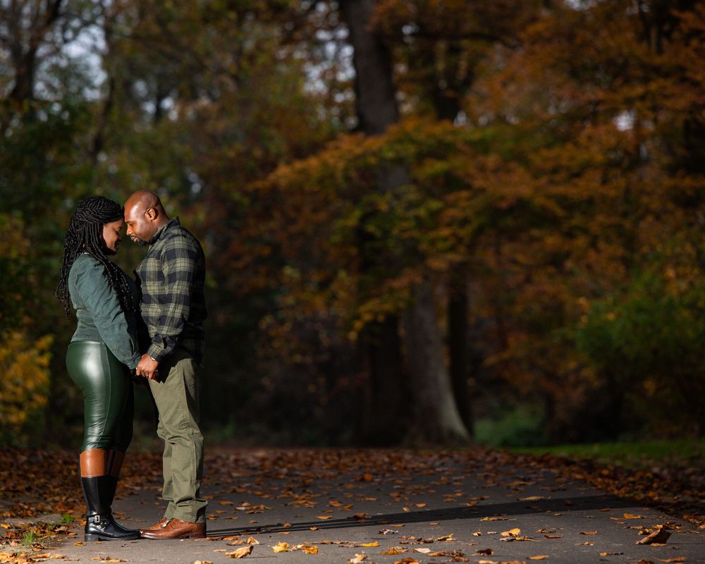 Romantic couple embraces on wooden bridge surrounded by fall foliage.