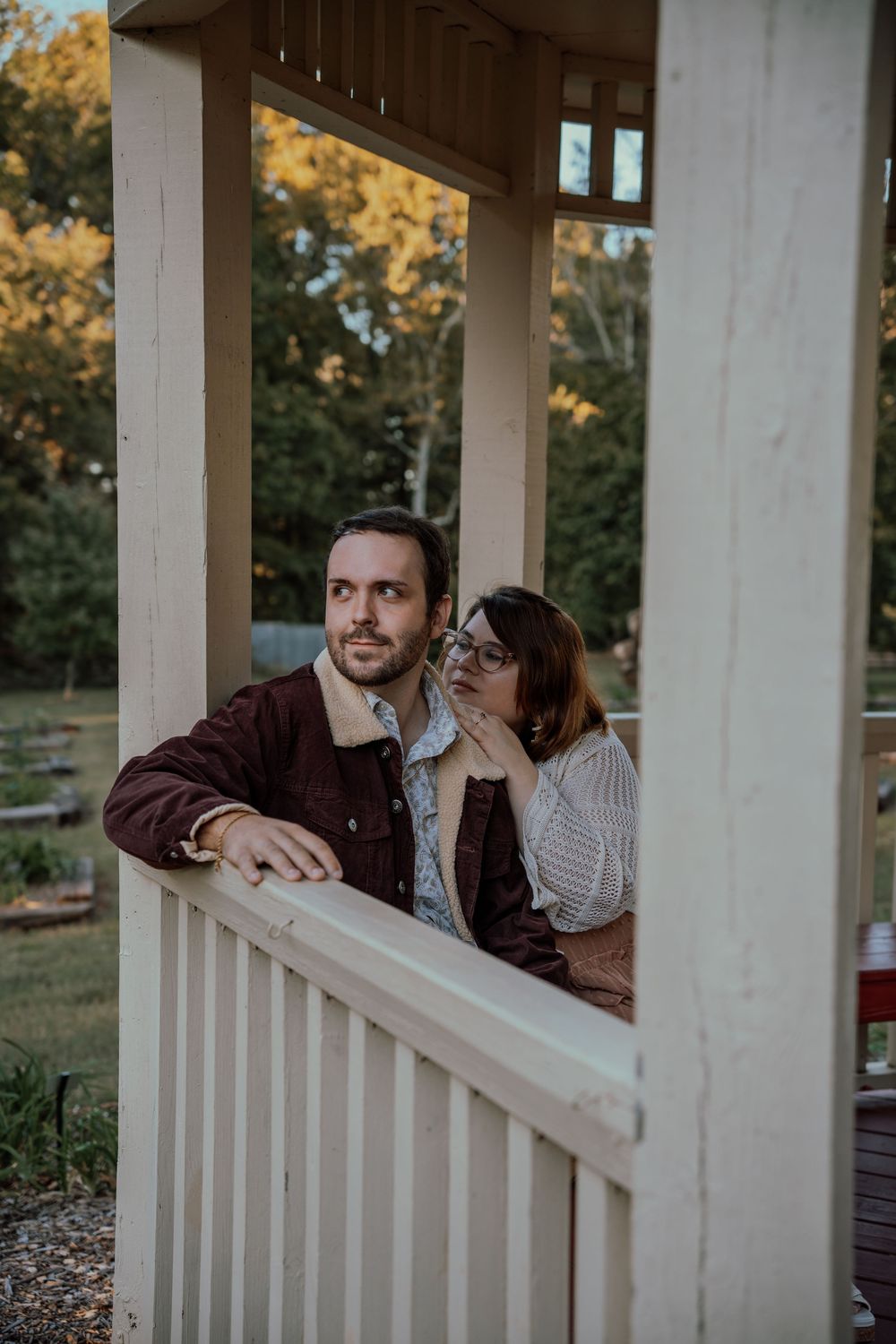 A couple shares tender moments on a white porch railing at sunset.