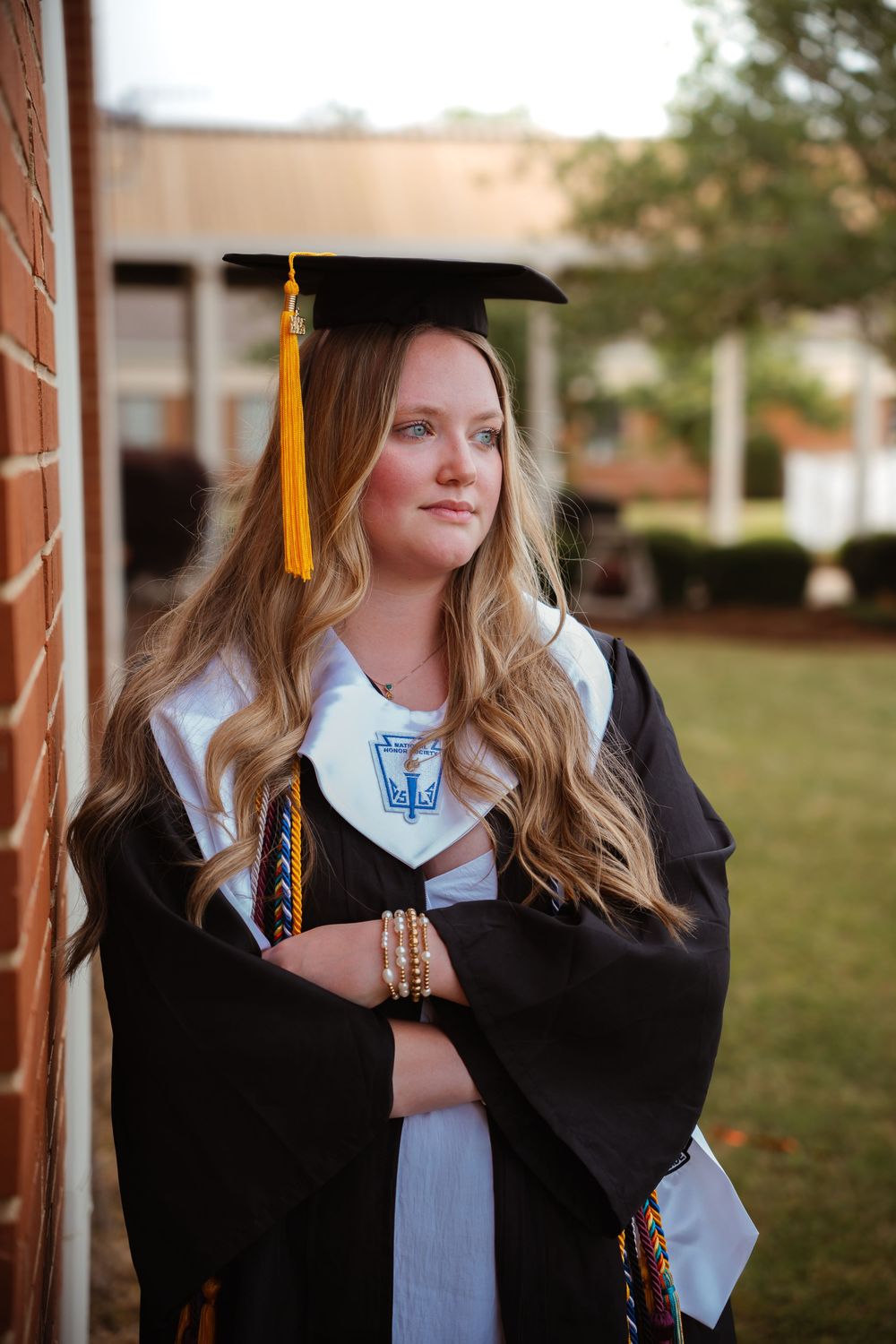 Graduate in cap and gown posing for portraits outdoors.