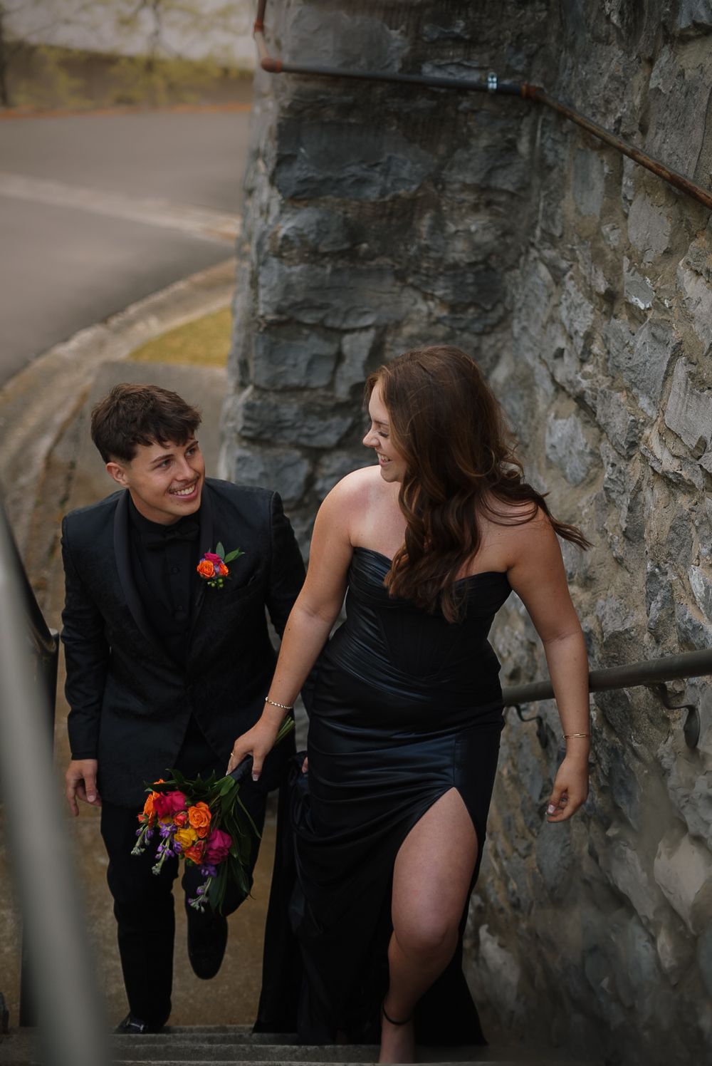 A playful moment captured against a stone wall with red flowers adding a pop of color.