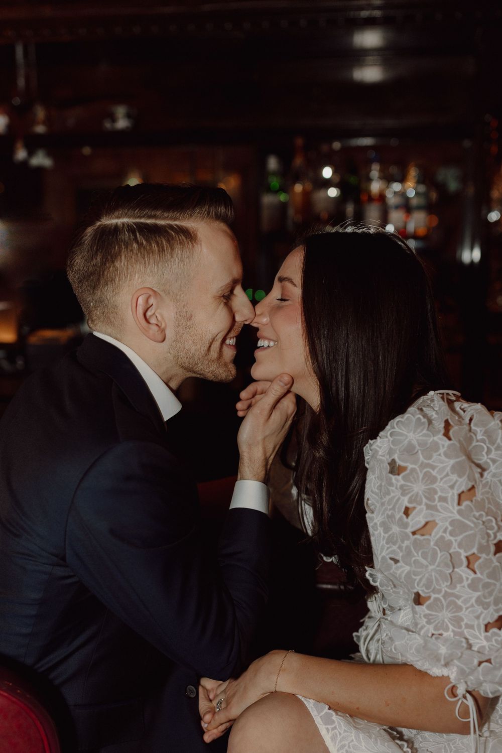 Romantic couple in formal wear sharing tender moments in a dark bar setting.
