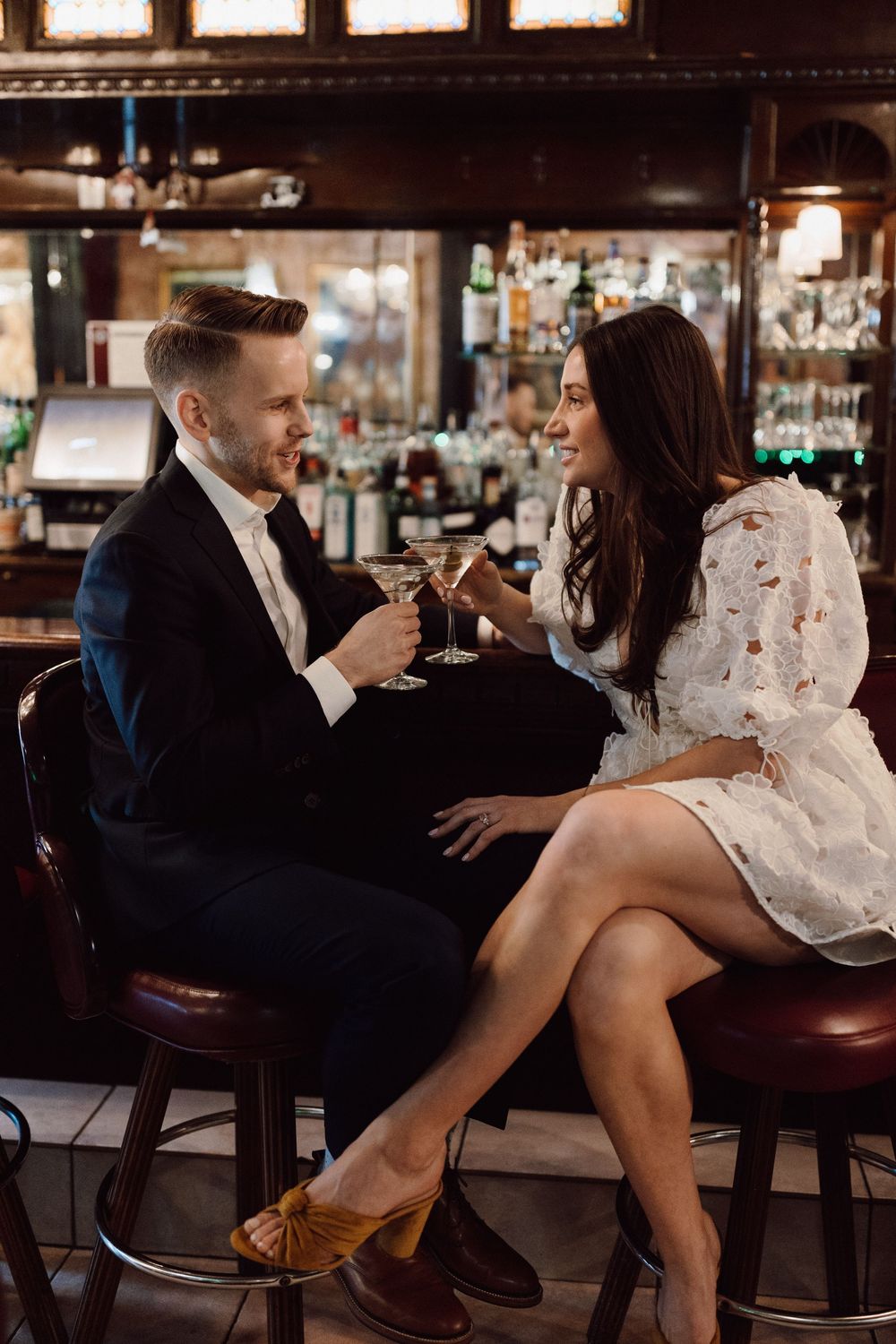 Couple in formal attire sharing drinks and intimate moments at an upscale bar.