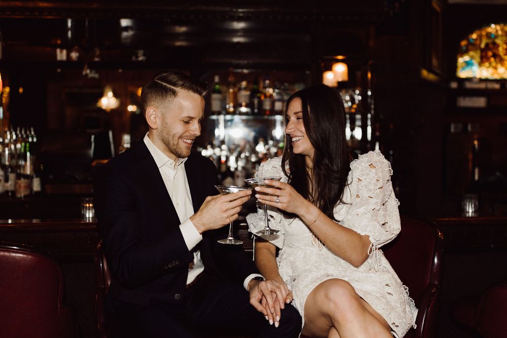 Couple sharing drinks at bar counter in elegant evening attire.