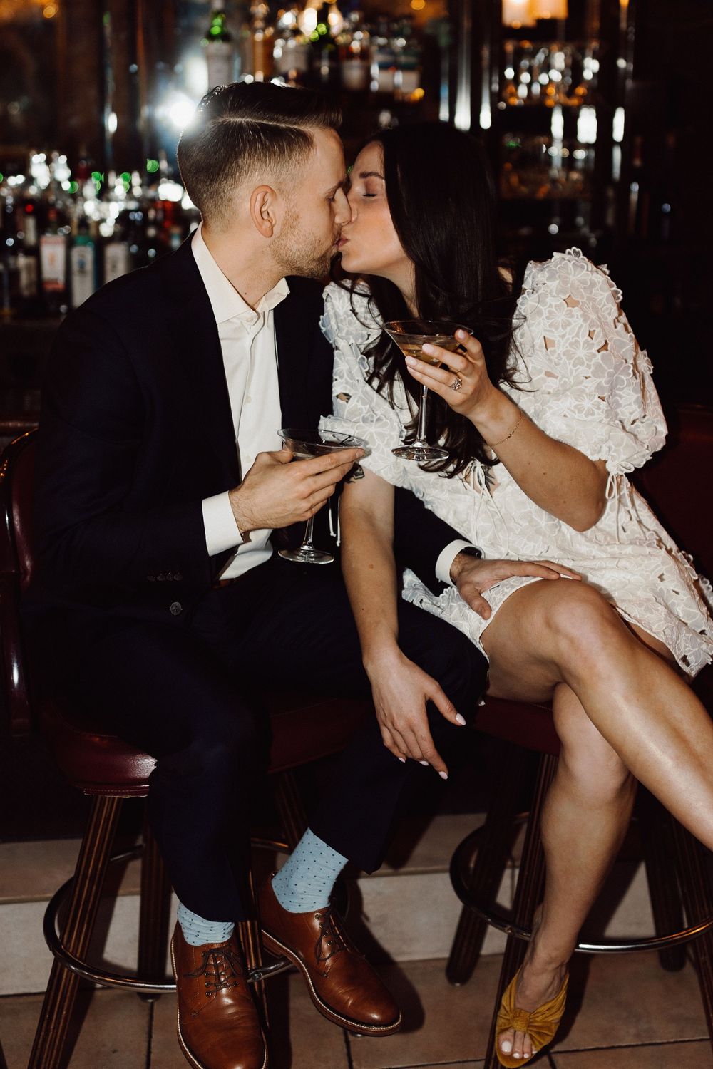 Romantic moment shared between couple enjoying martinis at dark bar.