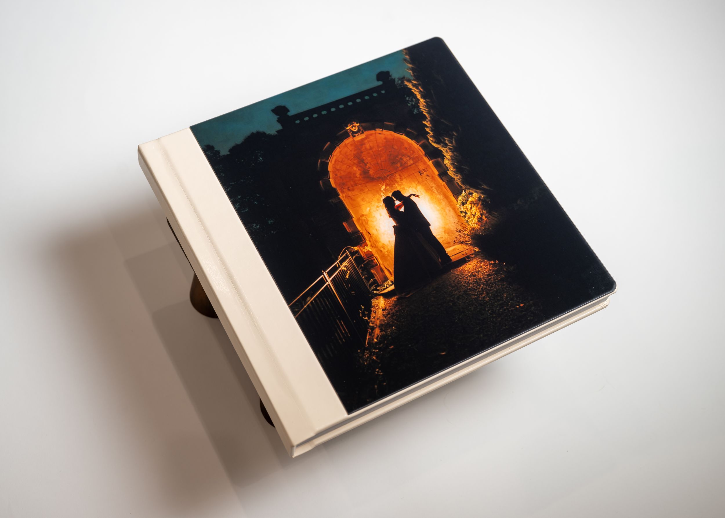A series of photos showing a hardcover book from different angles with a dark cover featuring orange glowing elements.