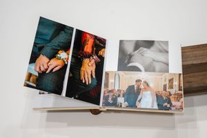 Open wedding album showing detail shots of rings and a ceremony celebration photo spread.