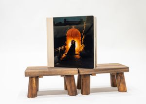 Silhouette of a couple against an orange sunset displayed on a rustic wooden bench display stand.