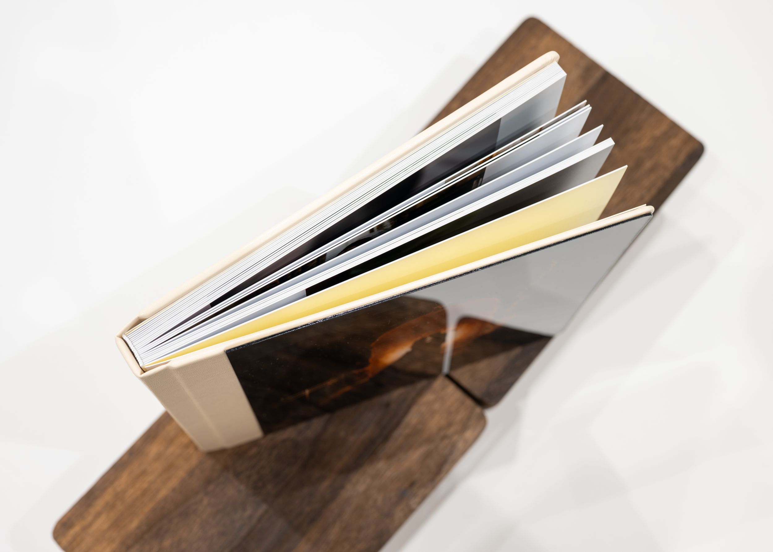 A partially opened hardcover book lies on a dark wooden surface with pages fanned out.