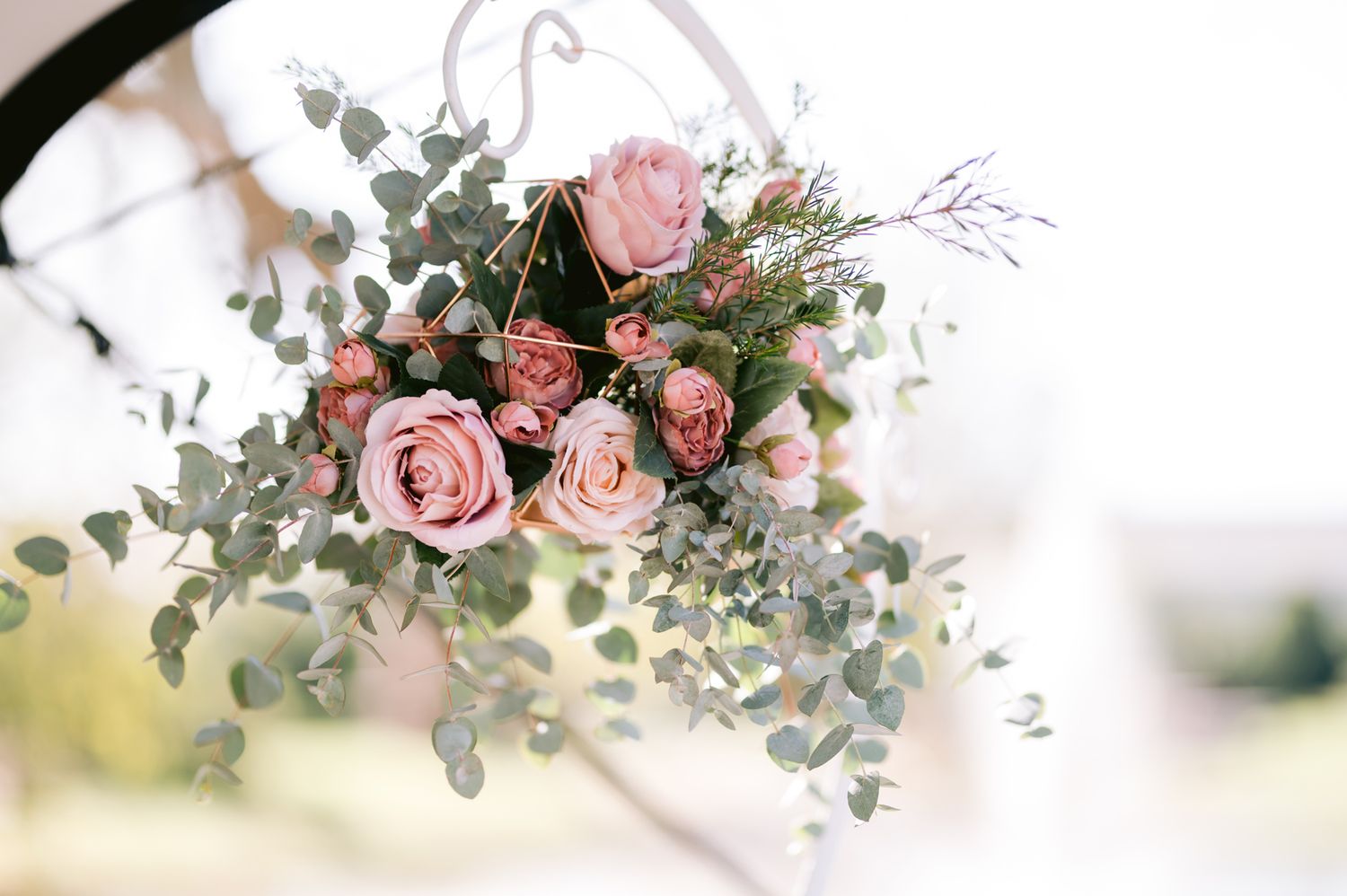 Delicate pink roses and eucalyptus greenery arranged in a romantic wedding bouquet against a soft blurred background.