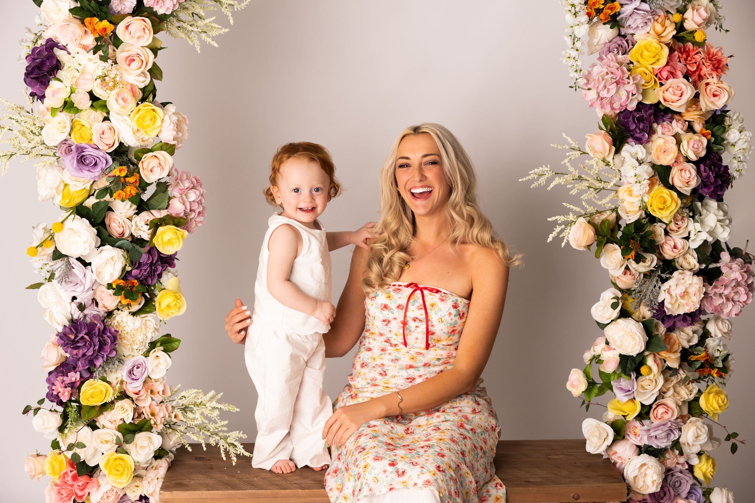 A floral backdrop with pink, yellow, purple and white flowers creates an elegant studio photography setting.