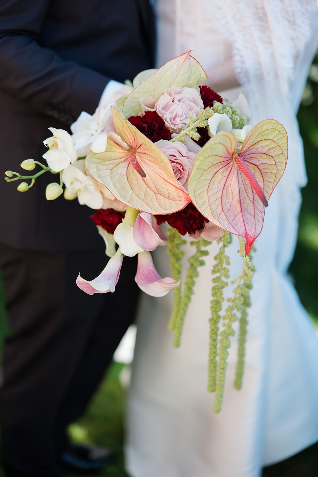 Close-up shots of pink anthurium flowers and orchids arranged in an elegant wedding bouquet with cascading greenery.