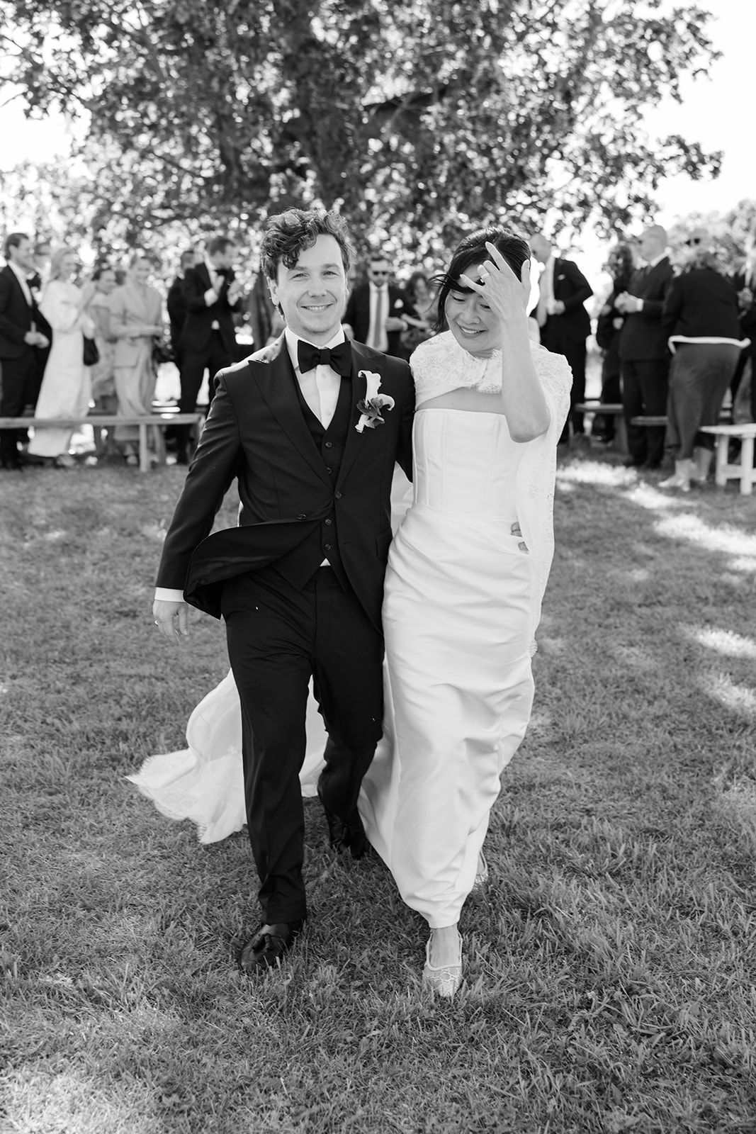 Black and white sequence of a couple walking and dancing together on grass during an outdoor wedding celebration.