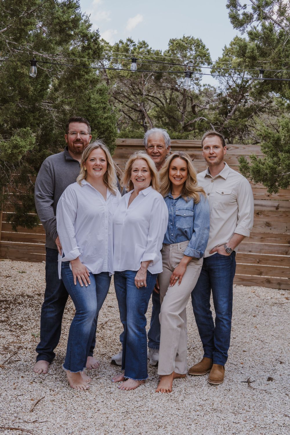 A group photo of six people outdoors against a wooden fence backdrop.