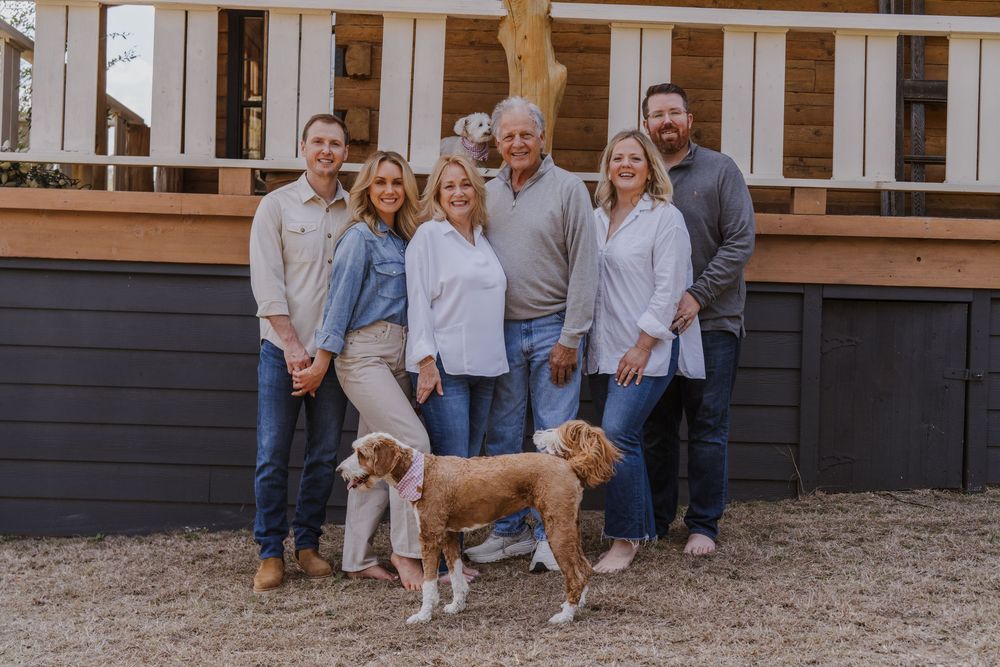 Extended family and pets gathered on front porch of rustic home.
