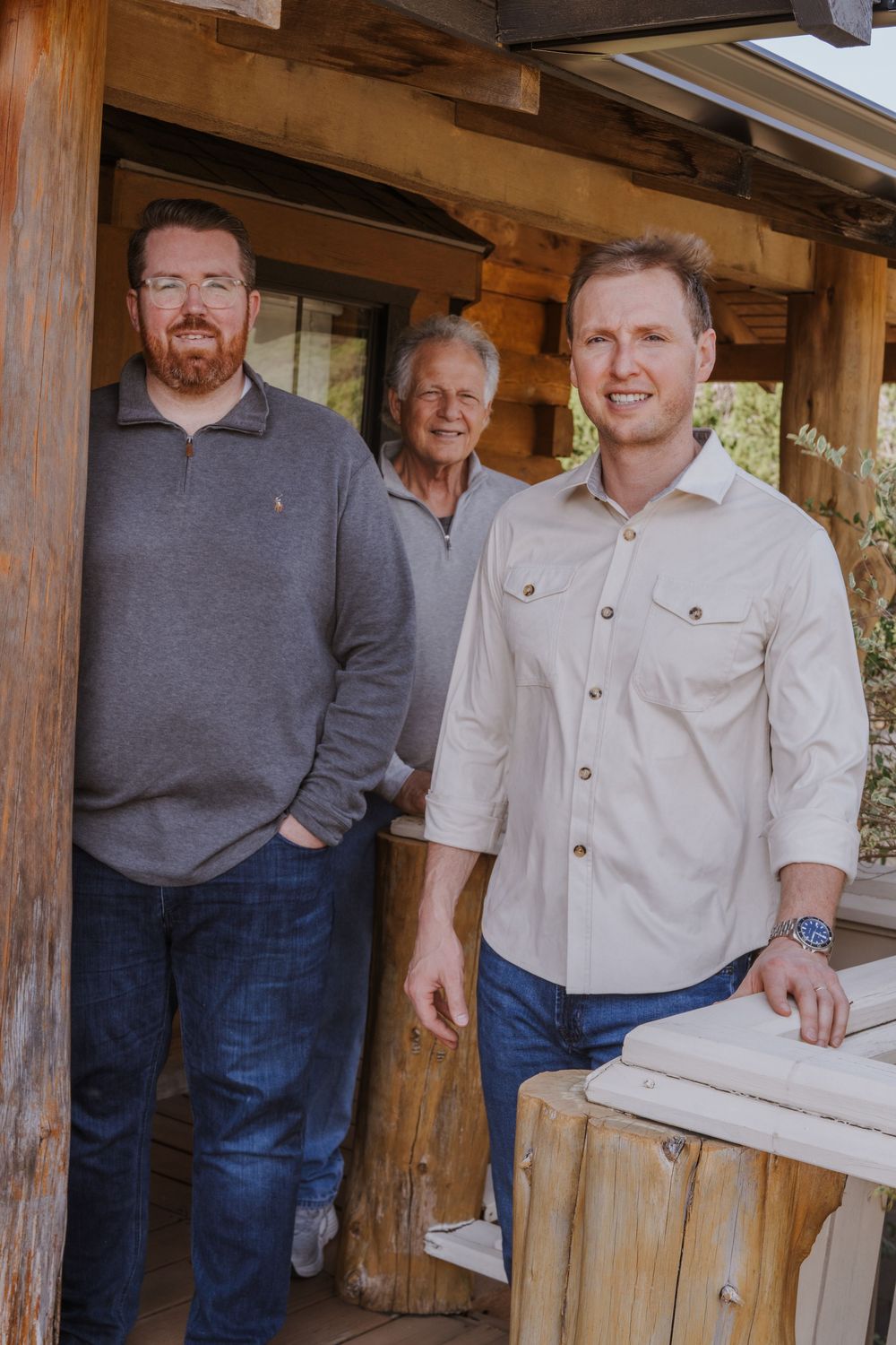 Group of people standing together on rustic wooden porch in casual attire.
