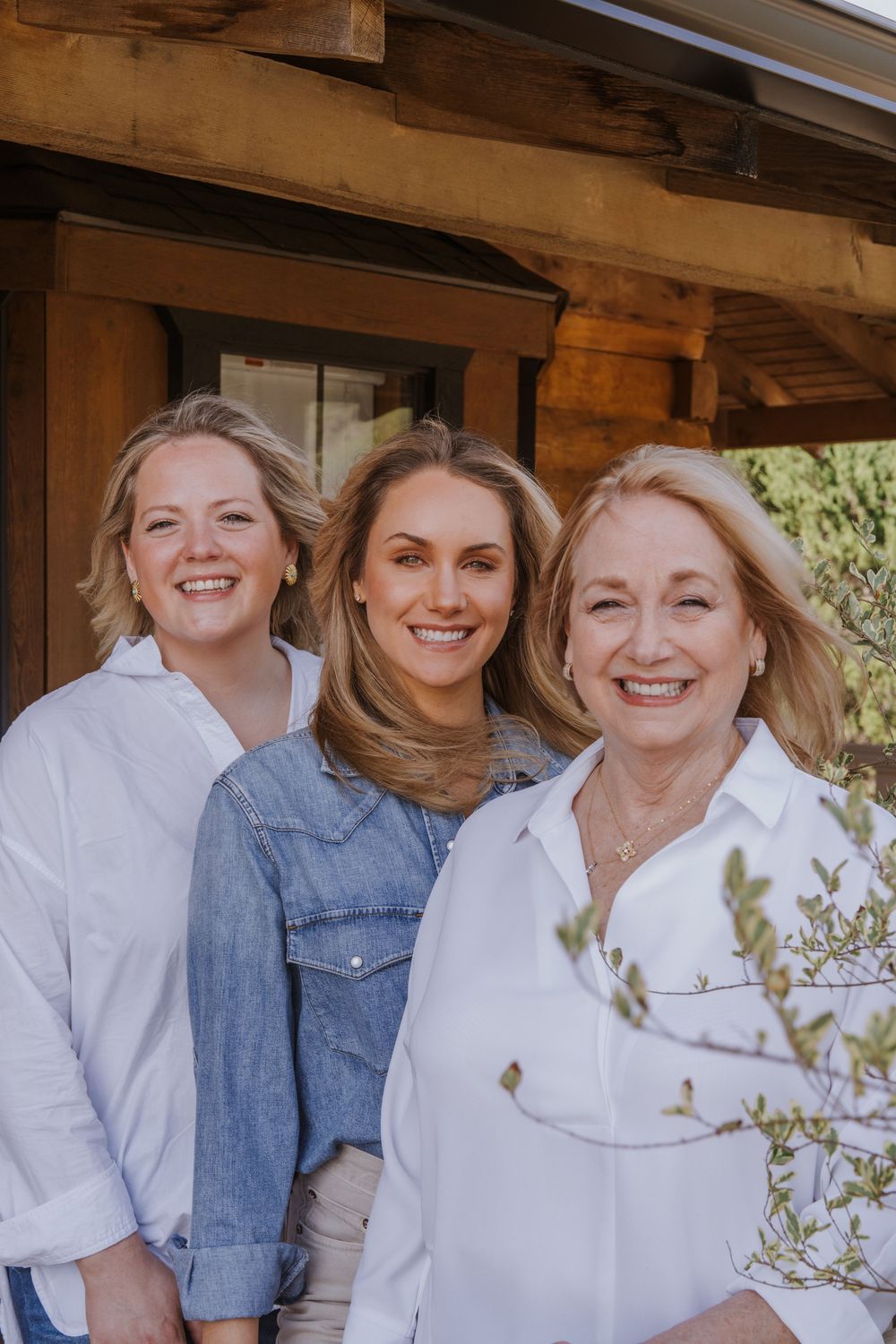 Group portrait of people in white and denim clothing on wooden porch.
