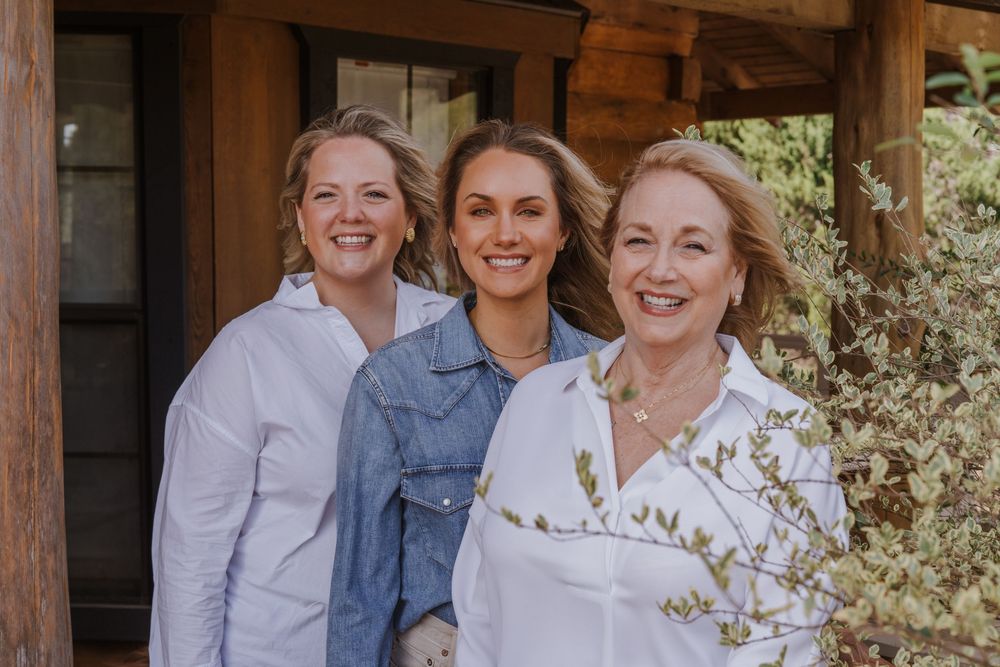 Group gathered on rustic wooden porch of cabin enjoying casual outdoor time together.