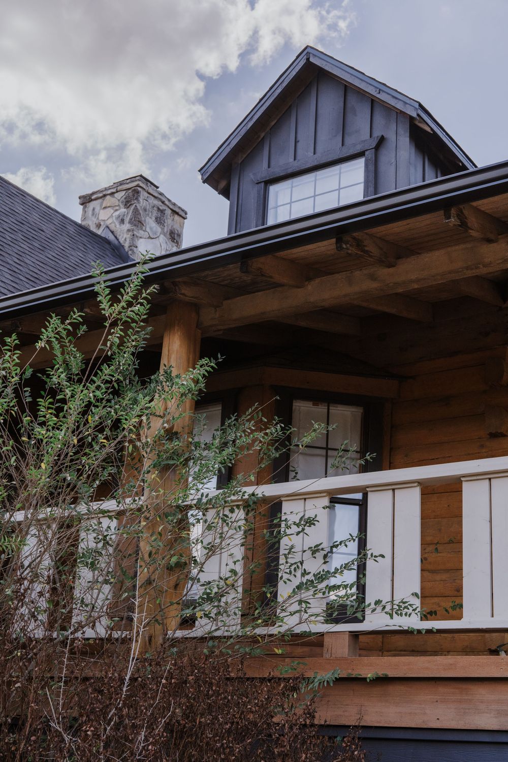 Architectural detail of wooden cabin exterior with white trim and stone accents.