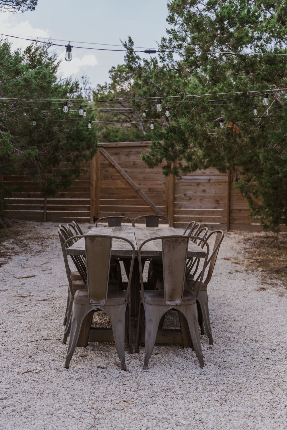 Outdoor dining area with metal chairs and tables on gravel patio.
