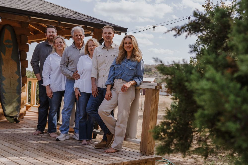 People gathered outside rustic cabin for casual outdoor event.