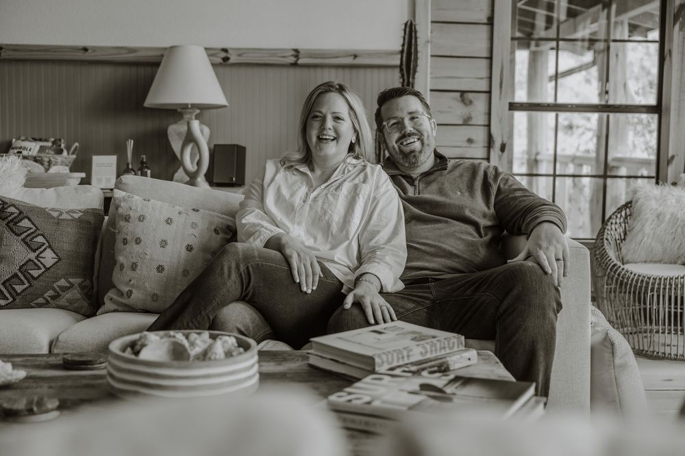 Black and white photo of a couple sharing a joyful moment on a comfortable couch.