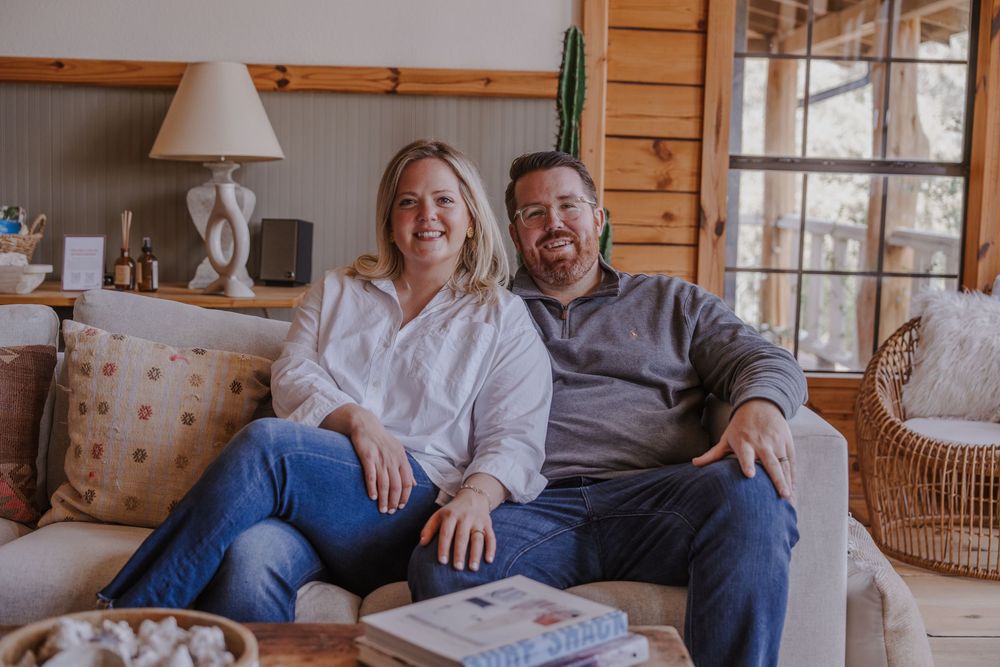 A cozy scene of two people relaxing together on a wooden cabin sofa with decorative pillows.
