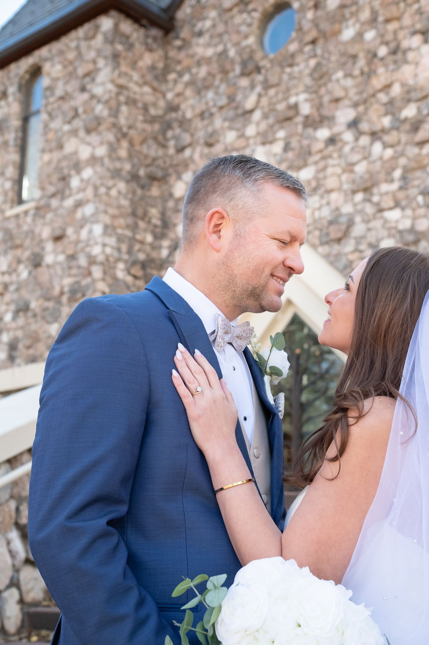 A romantic wedding kiss sequence showing multiple angles of the couple embracing against a stone wall background of The Beaver Creek Chapel