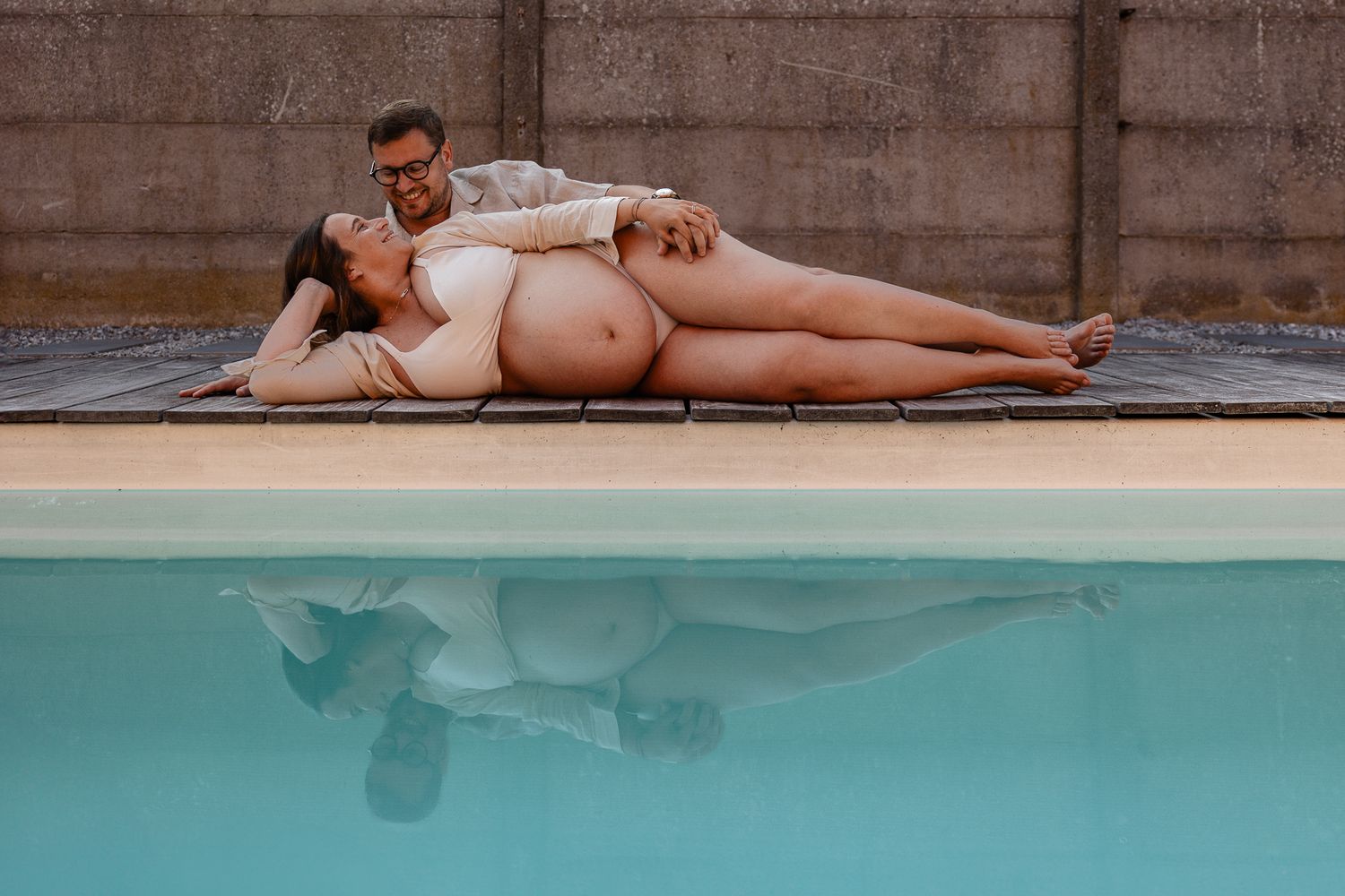 Trouver un photographe grossesse a Lille : reflets du couple dans l’eau de la piscine, seance photo femme enceinte Lille a domicile
