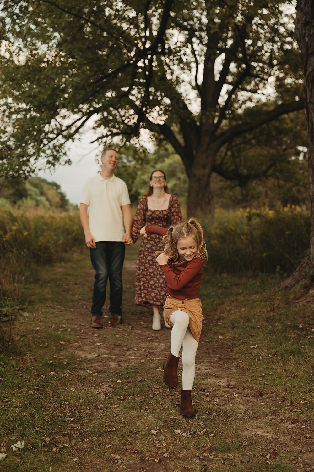 A family walks together on a wooded trail during golden hour, creating a warm and intimate outdoor portrait.