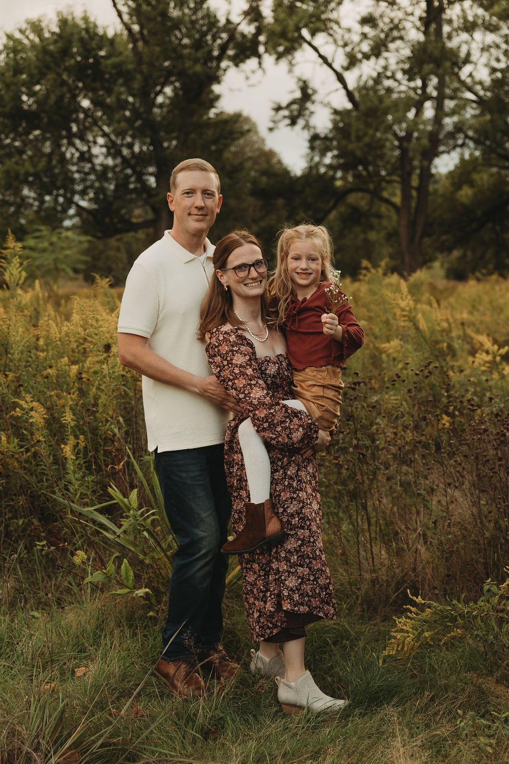A family shares joyful moments together in a golden field of tall grass during sunset.