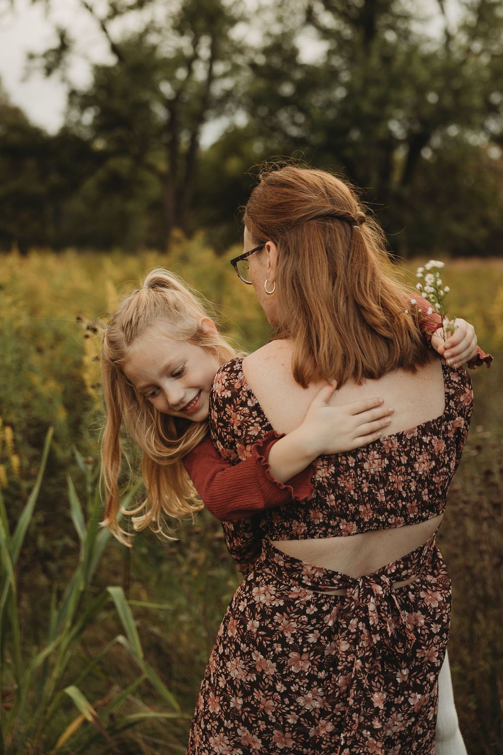 A joyful moment captured in a wildflower field as a pair share an embrace while wearing floral and burgundy outfits.