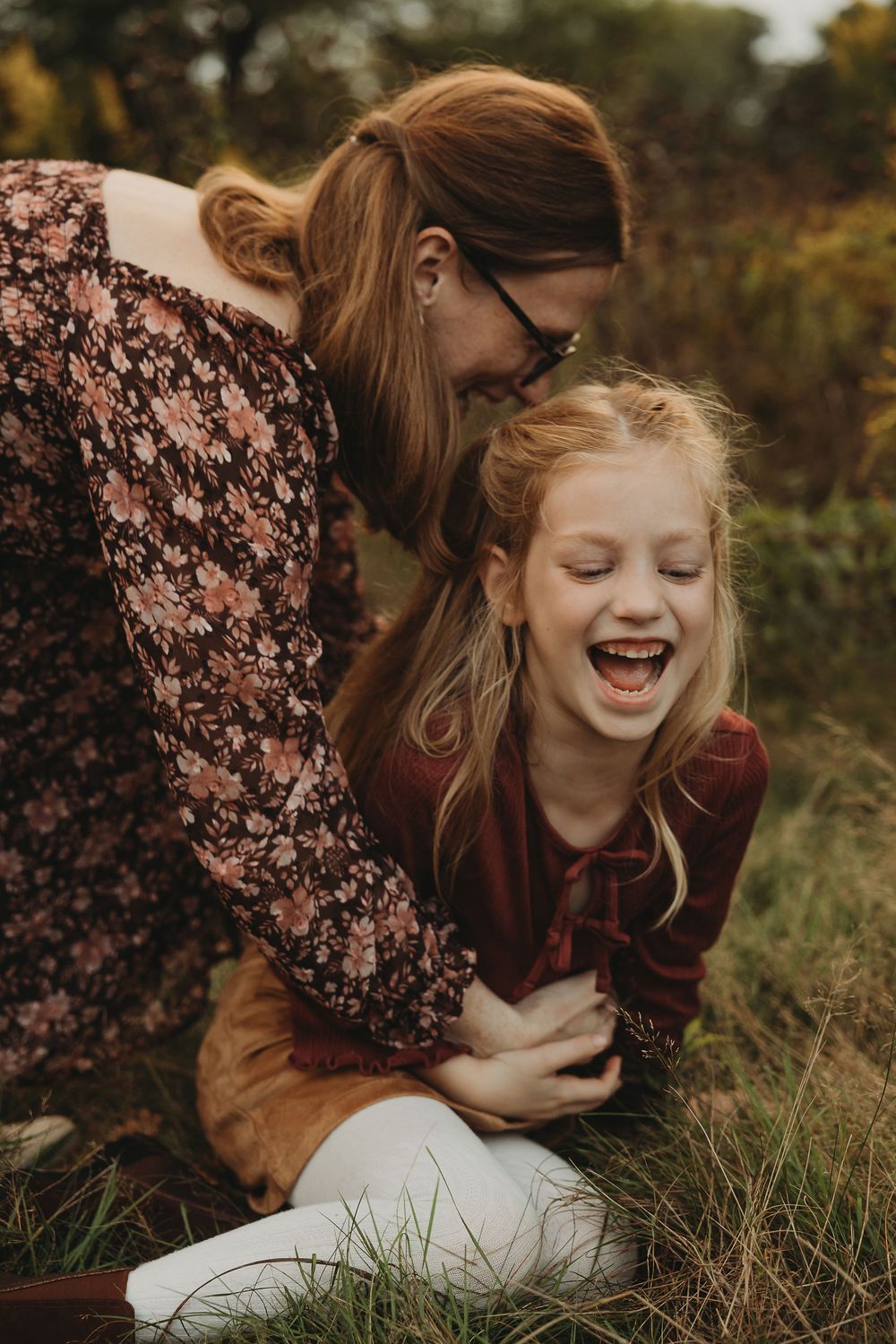 A joyful moment captured in warm autumn tones as someone plays with their fluffy white dog in tall grass.