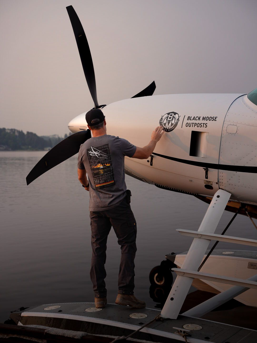 Small private aircraft parked at waterfront during sunset.