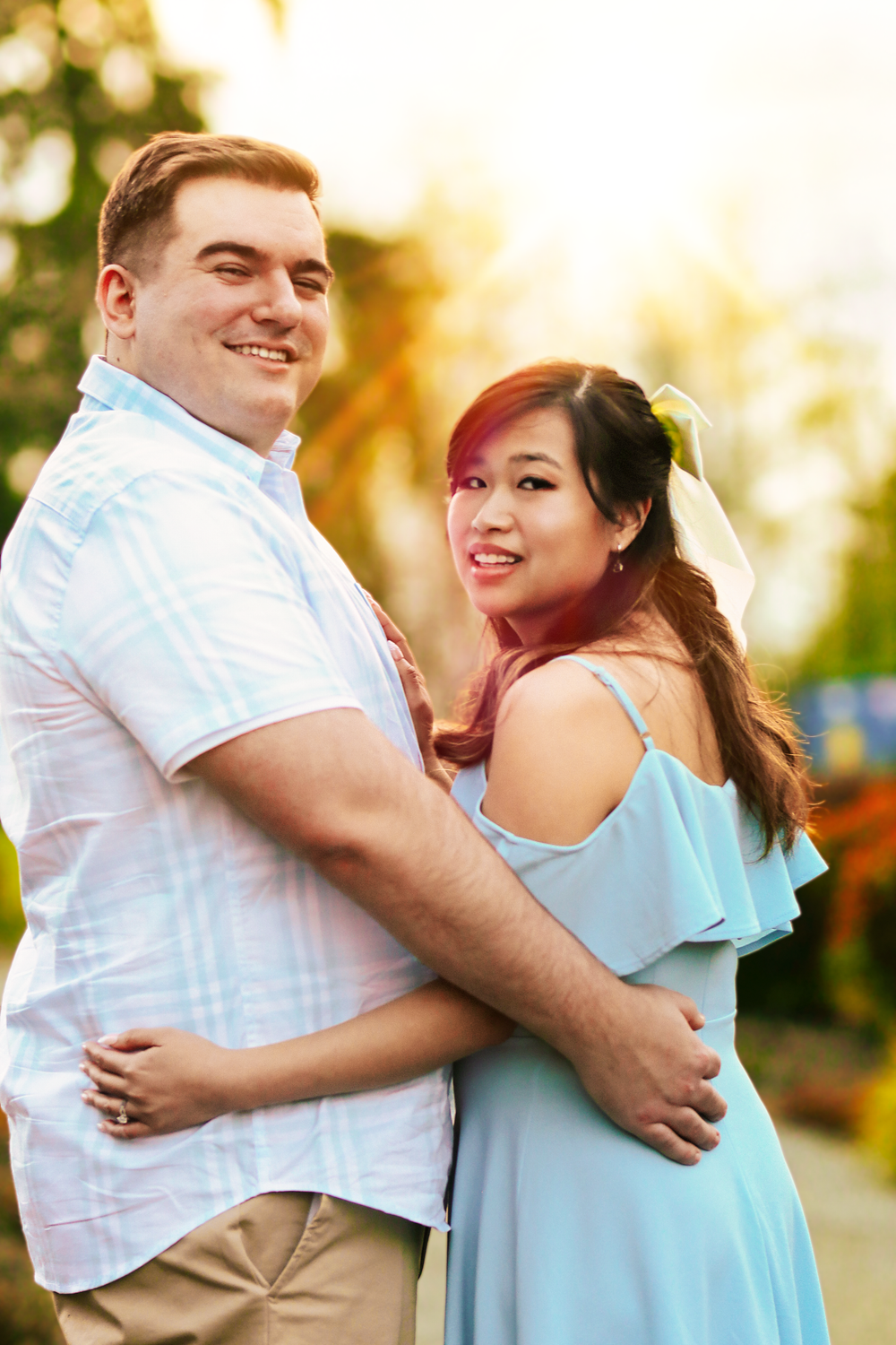 A romantic couple embracing and laughing together during golden hour sunset.
