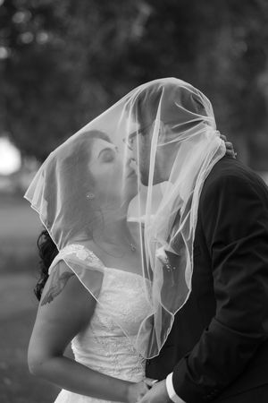 A romantic black and white wedding photo series showing a couple embracing under a delicate veil.