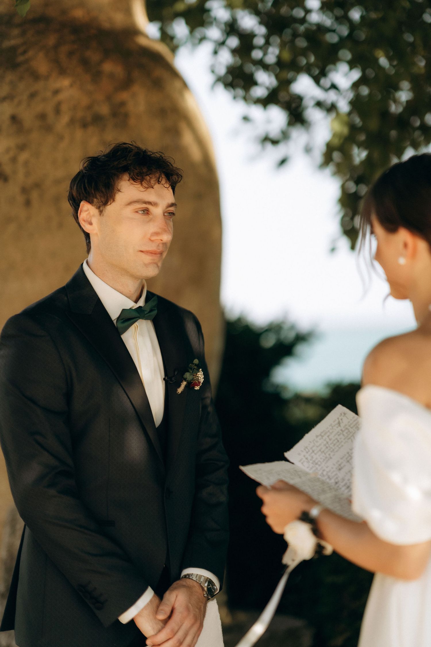 Couple exchanging vows or reading letters during an outdoor wedding ceremony.