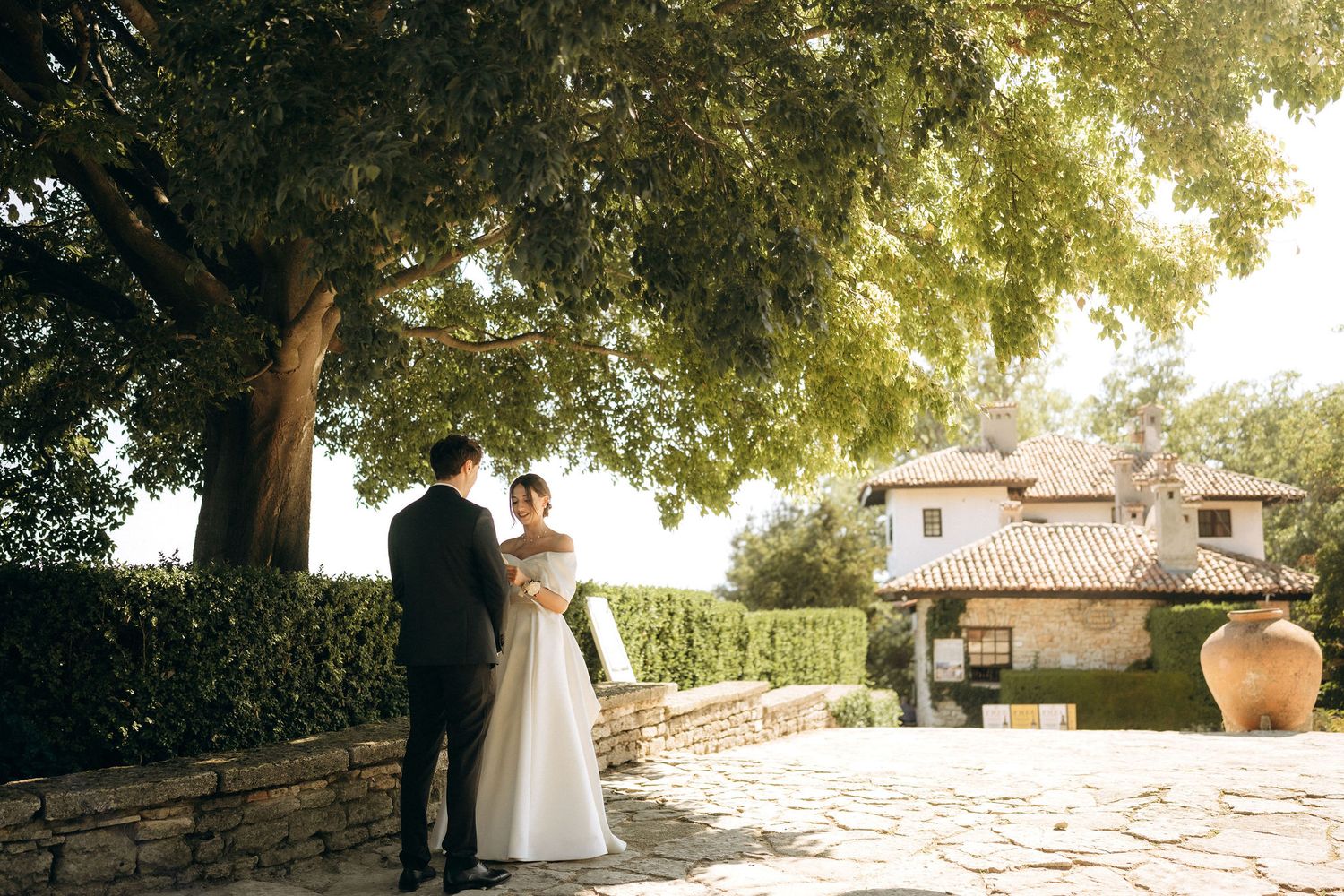 Garden wedding venue with stone pathways and trees creating natural shade.