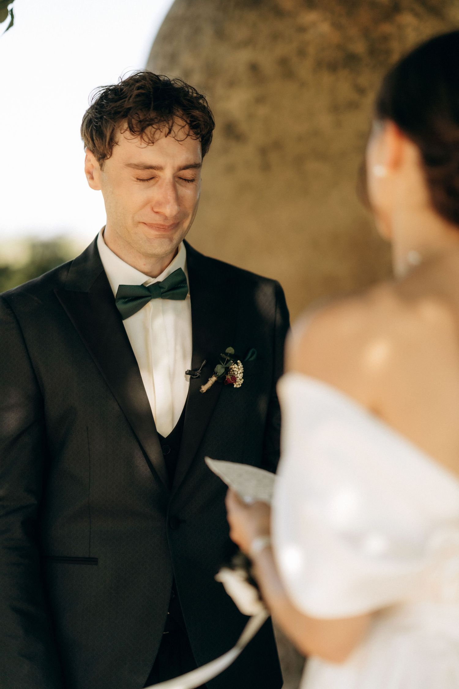 A couple exchanging vows during their outdoor wedding ceremony with the groom reading from paper.