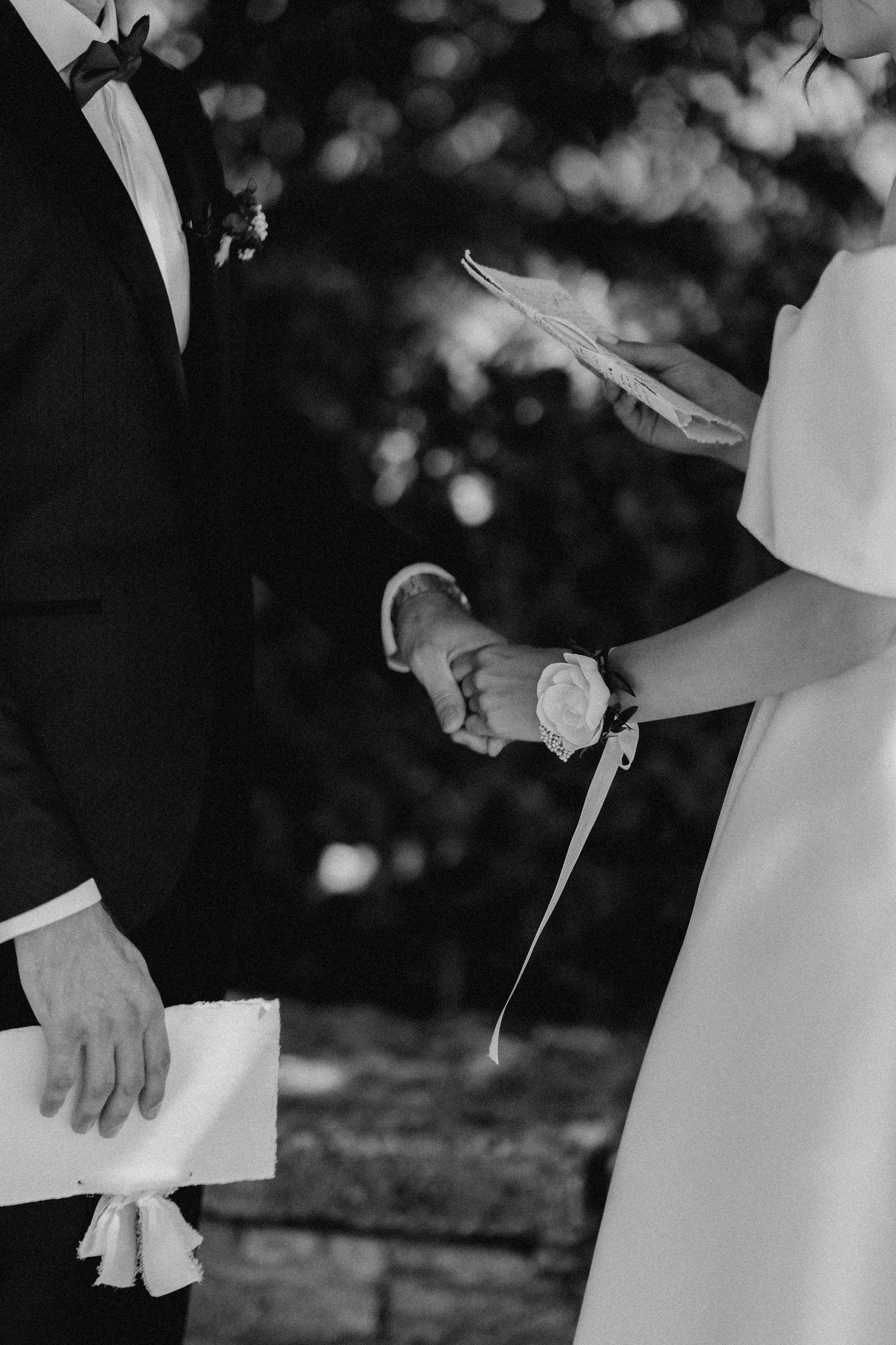 Black and white photo of newlyweds holding papers during their wedding vow exchange.