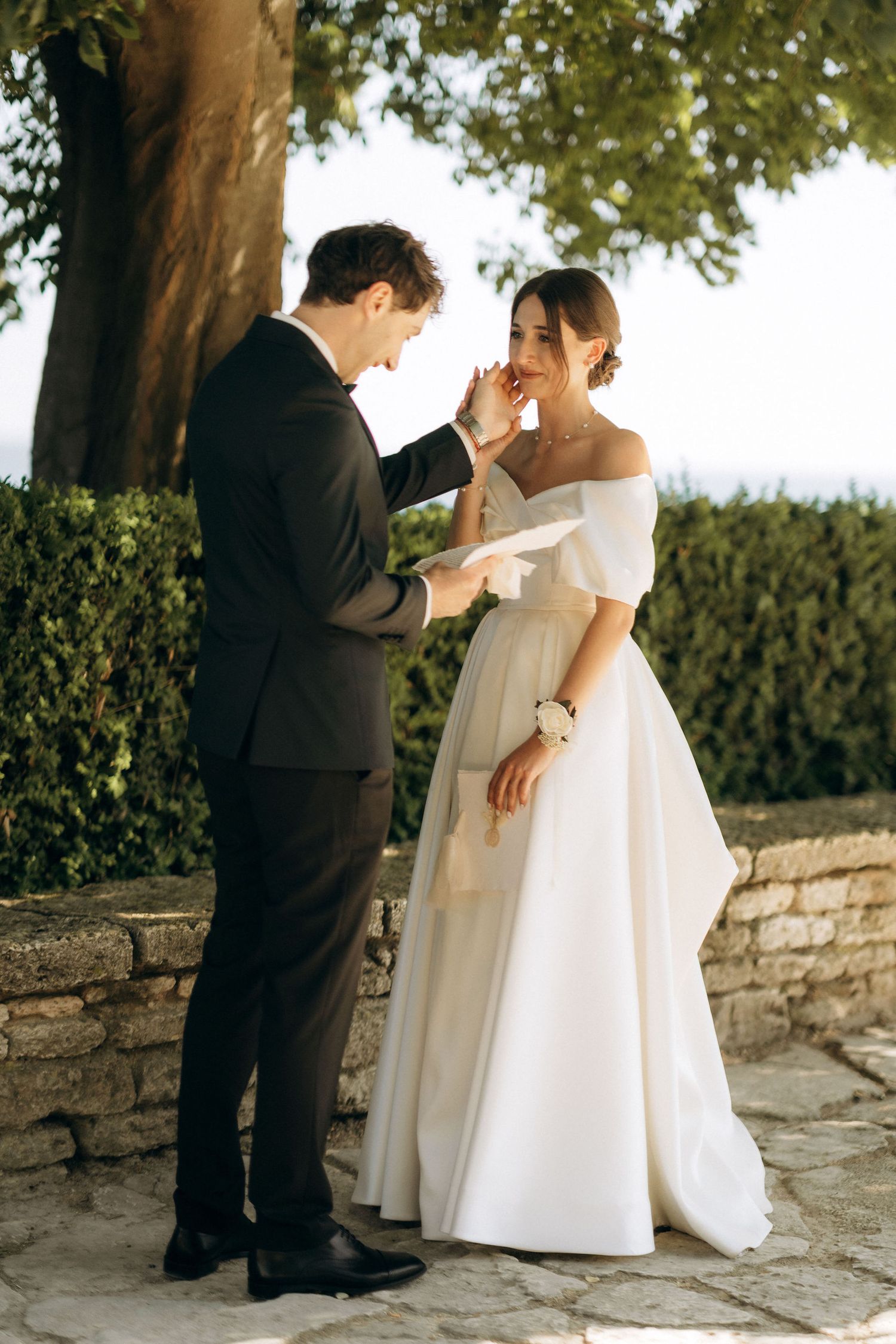 A tender moment between newlyweds as they read their vows on a stone terrace.