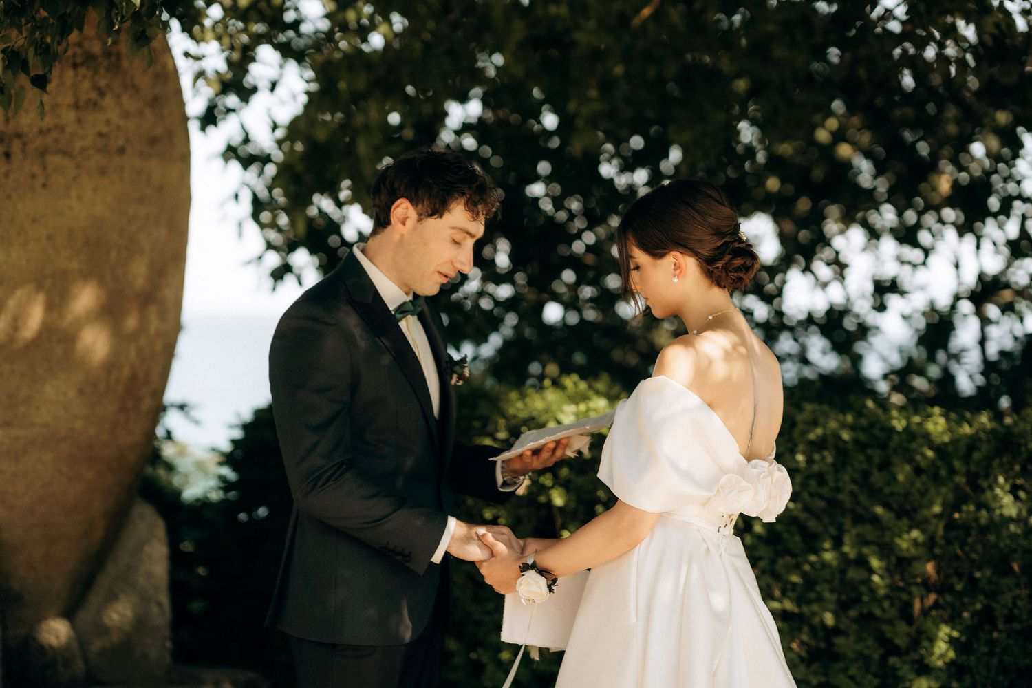 A couple shares a tender moment while exchanging rings during their garden ceremony.