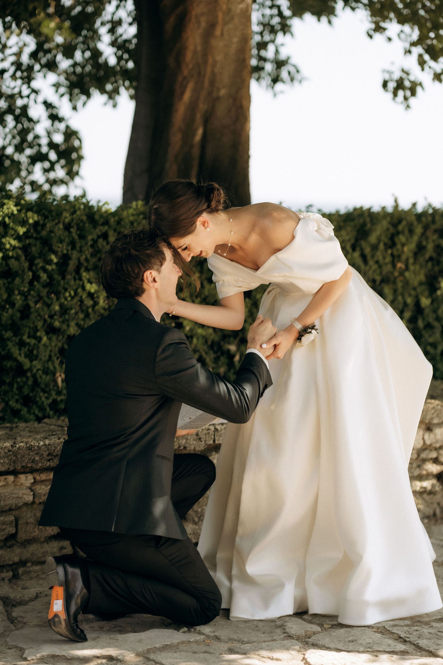 A romantic proposal moment captured in a garden setting with stone pathway.